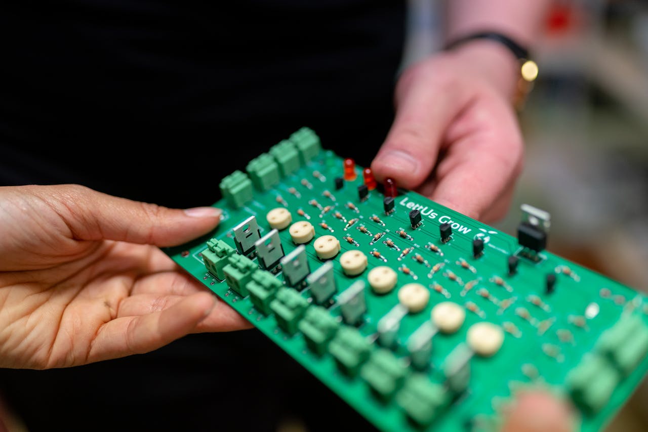 Hands holding a green printed circuit board.